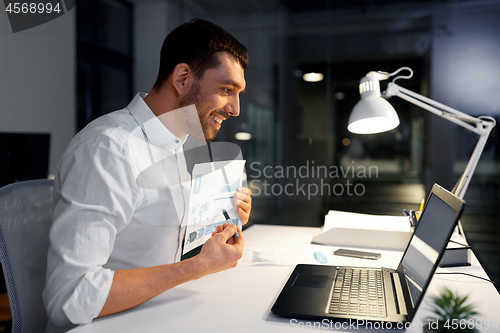 Image of businessman having video chat at night office