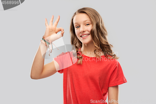 Image of smiling teenage girl in red t-shirt showing ok