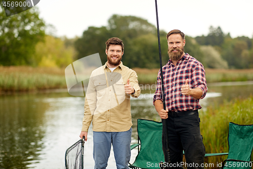 Image of happy friends with fishing rods showing thumbs up