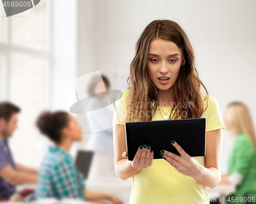 Image of astonished student girl with tablet pc at school