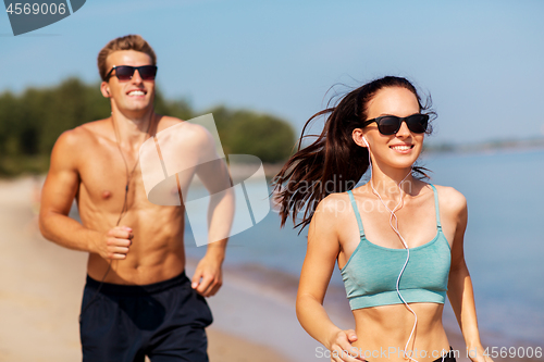 Image of couple with earphones running along on beach