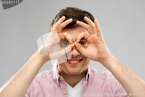 Image of young man looking through finger glasses