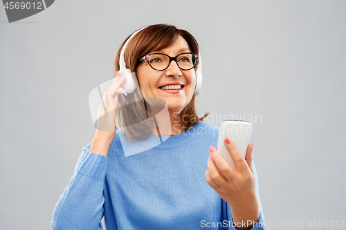 Image of senior woman in headphones listening music on cell