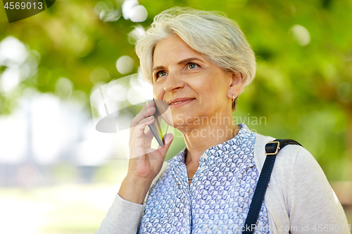 Image of senior woman calling on smartphone in summer park