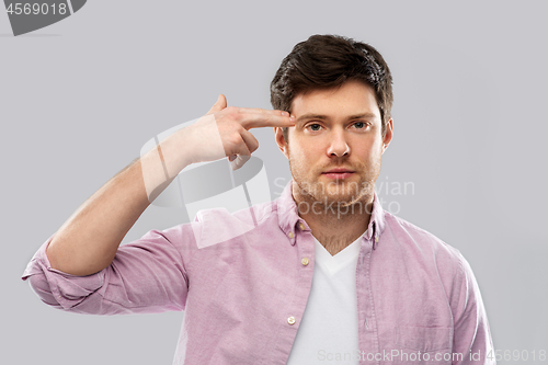 Image of bored man making headshot by finger gun gesture