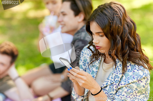 Image of woman using smartphone at picnic with friends