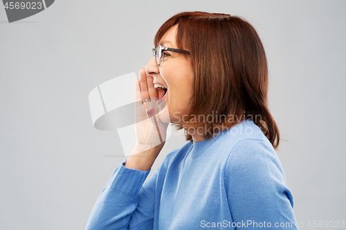 Image of senior woman in glasses calling over grey