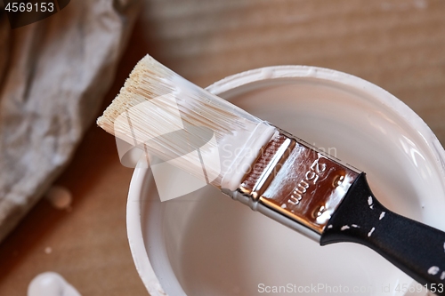 Image of Paint brush on a can of white wall paint
