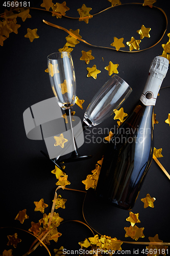 Image of Glasses and bottle of champagne with golden serpentines and confetti