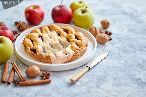 Image of Tasty sweet homemade apple pie cake with cinnamon sticks, walnuts and apples