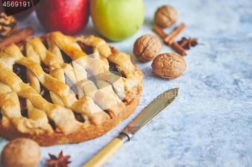 Image of Tasty sweet homemade apple pie cake with cinnamon sticks, walnuts and apples