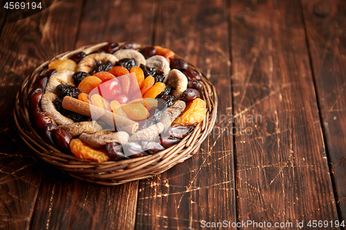 Image of Mix of dried fruits in a small wicker basket on wooden table