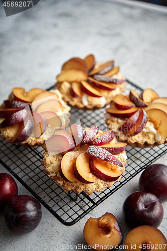 Image of Homemade crumble tarts with fresh plum slices placed on iron baking grill