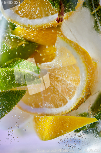 Image of Slices of lemon and lime with bubbles of water in a glass. Macro photo of refreshing lemonade