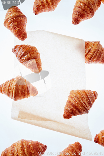 Image of Floating freshly baked croissant on a light background of parchment paper, mock up.