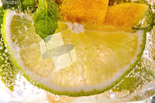 Image of Macro photo of a summer mojito cocktail with slices of lime, lemon and mint leaves in a glass.