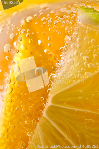 Image of Macro photo of yellow lemon slices with lots of bubbles in a glass with water. Summer cold lemonade