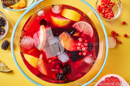 Image of Top view on glass jug with homemade fruit berry drink with ice cubes on yellow background