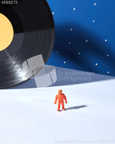 Image of Astronaut in outer space agaimst of black vinyl record and duotone blue white background