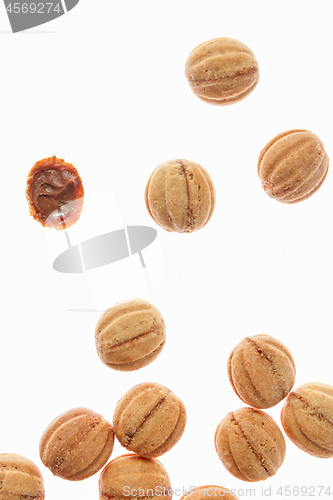 Image of Falling cookies walnuts with milk cream on a white background.