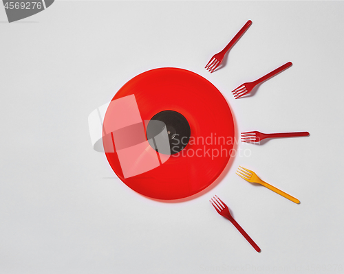 Image of Red vinyl record with plastic colorfut forks on a gray background.