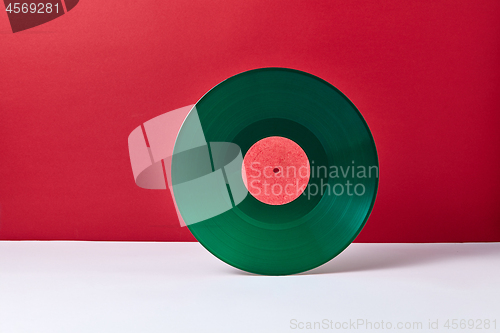 Image of Vintage green vinyl record disk on a duotone background.
