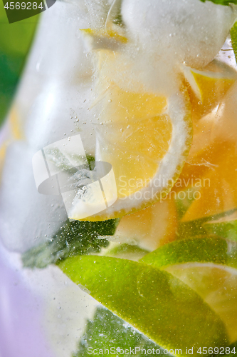 Image of Refreshing cocktail in a glass with citrus slices and mint in a glass.