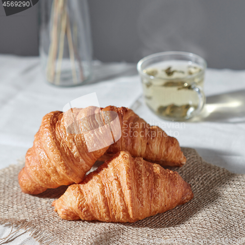 Image of Close up homemade fresh croissants and green tea on a gray background.