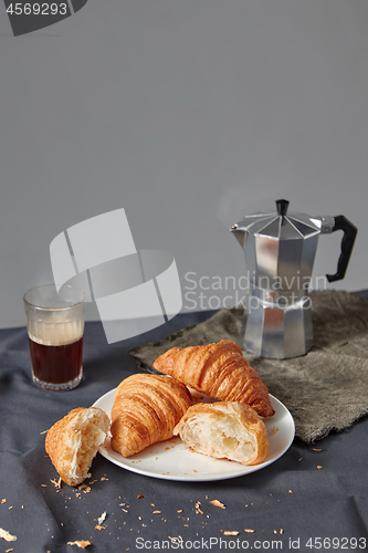 Image of Continental breakfast with fresh croissant and natural coffee on a grey background.