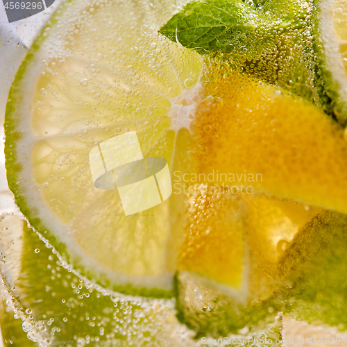 Image of Macro background of lemonade with pieces of lemon and bubbles of air.