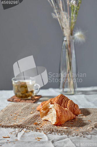 Image of Breakfast still life with green tea and fresh croissanta on a grey background.