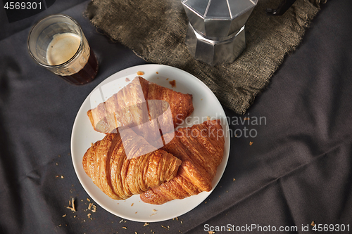 Image of Coffee glass with freshly baked homemade croissants on a dark gray table