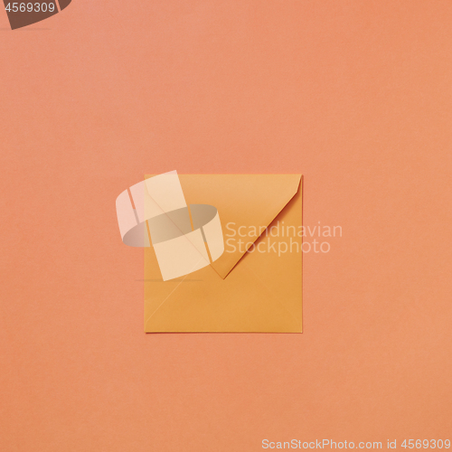 Image of Empty handmade mock up envelope on a peach color background .