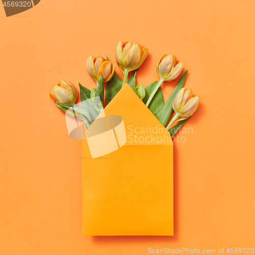 Image of Mock up envelope with yellow tulips on an orange background.