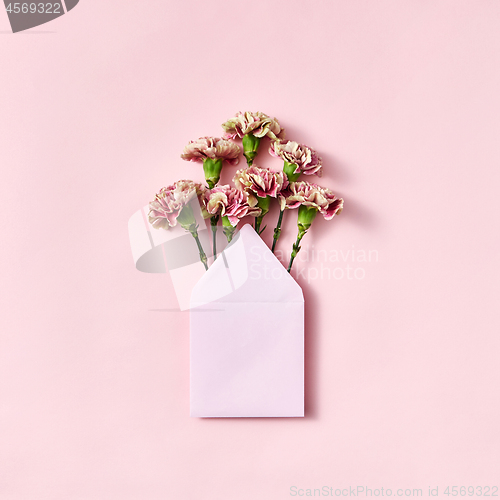 Image of Mock up envelope with pink carnations for congratulation on a pastel pink background.