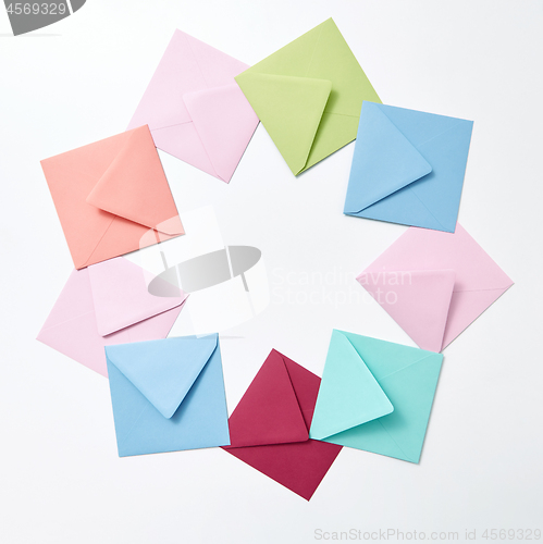 Image of Round frame of colored craft blank envelopes on a light background.