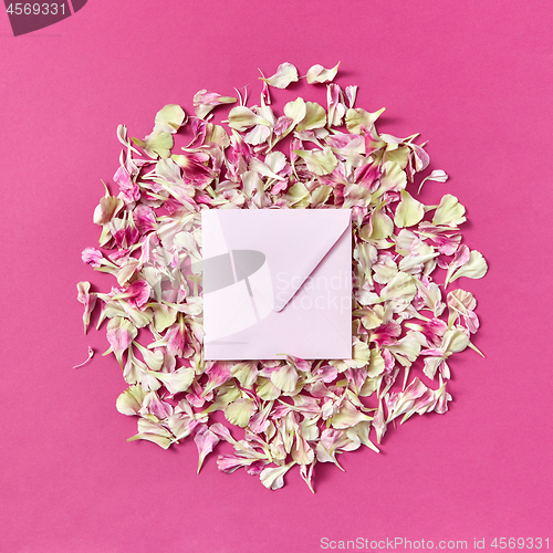 Image of Mockup handmade envelope on a round frame from petals on a magenta background.