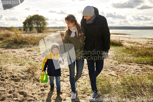 Image of happy family walking along autumn beach