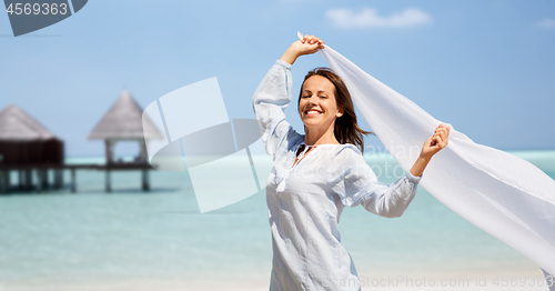 Image of happy woman with shawl waving in wind on beach