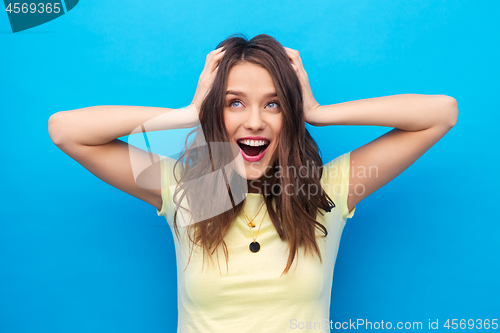 Image of smiling young woman holding to her head