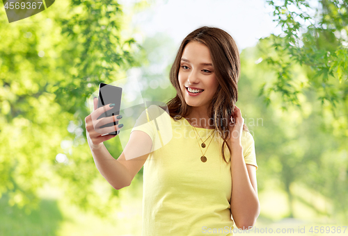 Image of smiling teenage girl taking selfie by smartphone