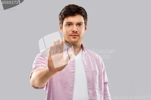 Image of serious young man showing stop gesture