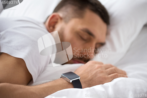 Image of close up of man with smart watch sleeping in bed