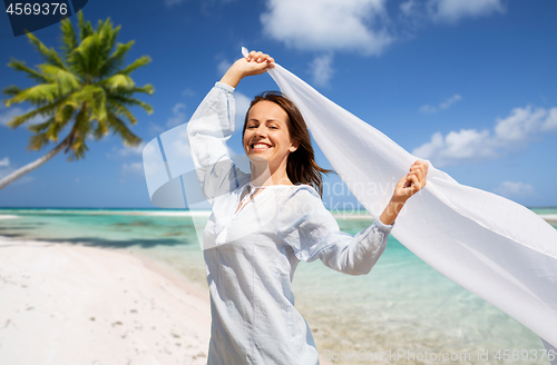 Image of happy woman with shawl waving in wind on beach