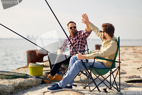 Image of happy friends with fishing rods on pier