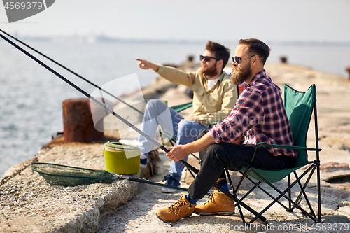 Image of happy friends with fishing rods on pier