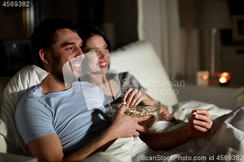 Image of couple with popcorn watching tv at night at home