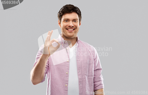 Image of smiling young man showing ok hand sign