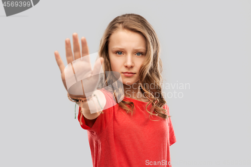 Image of serious teenage girl showing stop gesture