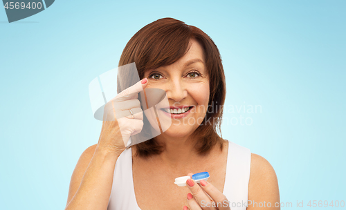 Image of happy senior woman applying contact lenses